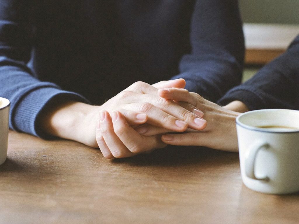 Two people's hands resting together on a table